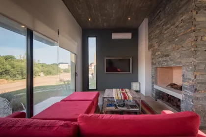 Living moderno con chimenea de piedra y grandes ventanales — proyecto Costa Esmeralda 3, por Arquitecto Caceres, en Costa Esmeralda