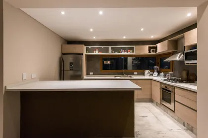 Cocina moderna con isla, muebles de madera y suelo de mármol — proyecto Costa Esmeralda Casa MAI Lote 374 Deportiva, por Arquitecto Caceres, en Costa Esmeralda
