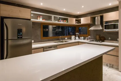 Cocina moderna con isla blanca y muebles de madera clara — proyecto Costa Esmeralda Casa MAI Lote 374 Deportiva, por Arquitecto Caceres, en Costa Esmeralda