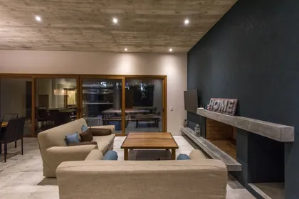 Living moderno con techo de hormigón visto y pared oscura — proyecto Costa Esmeralda Casa MAI Lote 374 Deportiva, por Arquitecto Caceres, en Costa Esmeralda