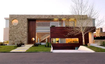Fachada moderna con piedra, madera y grandes ventanales — proyecto Casa Cardales, por Barrionuevo Arquitects, en Los Cardales