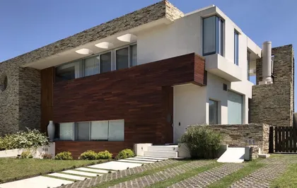 fachada moderna con piedra y madera — proyecto Casa Cardales, por Barrionuevo Arquitects, en Los Cardales