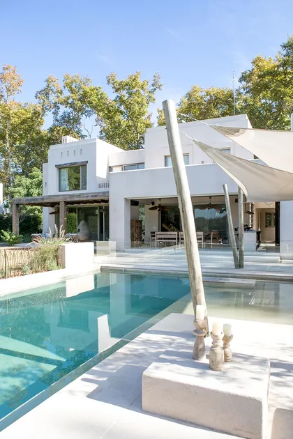 Casa moderna con piscina y toldo bajo cielo azul — proyecto Aires Orientales, por Ricardo Pereyra Iraola