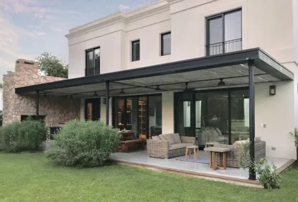 Amplio patio moderno con pérgola, muebles de exterior y jardín — proyecto Barrio Mayling, por Estudio Moreto Bensusan, en Pilar