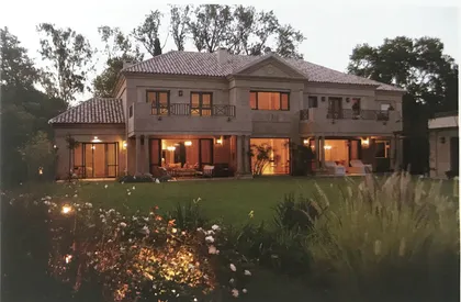 Fachada moderna de piedra y madera con grandes ventanales y pérgola — proyecto La Horqueta II, por Estudio Moreto Bensusan, en San Isidro