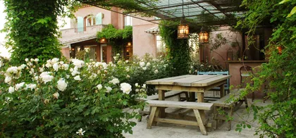 Patio rústico con flores blancas, mesa de madera y pérgola — proyecto Laguna del Sol, por Estudio Moreto Bensusan, en Tigre