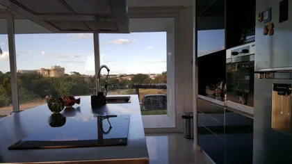 Cocina moderna con isla grande y vista a jardín — proyecto Costa Esmeralda, por Cuello Selva, en Costa Esmeralda