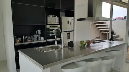 Cocina moderna con gabinetes negros y mesada de acero inoxidable — proyecto Costa Esmeralda, por Cuello Selva, en Costa Esmeralda