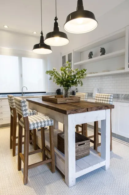 Cocina rústica con isla central de madera y taburetes tapizados — proyecto Casa Wehtje, por Estudio Magrane