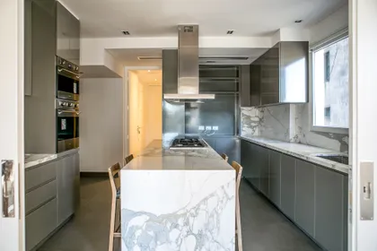 Cocina moderna con isla de mármol y muebles grises — proyecto Lafinur, por Estudio Magrane, en CABA