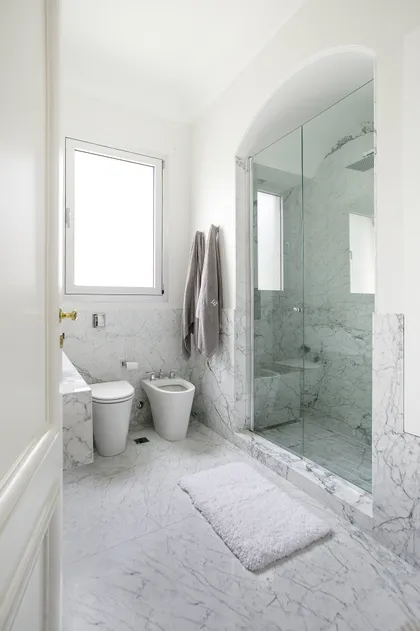 Baño moderno con paredes y pisos de mármol blanco — proyecto Libertador y Salguero, por Estudio Magrane, en CABA