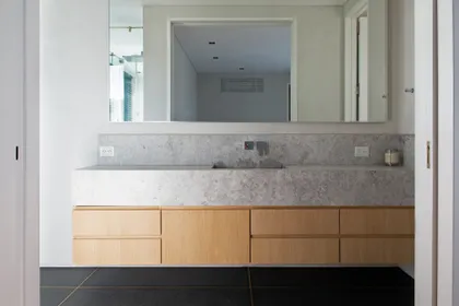 Baño moderno con mesada de mármol gris y mueble de madera — proyecto Los Patricios, por Estudio Magrane