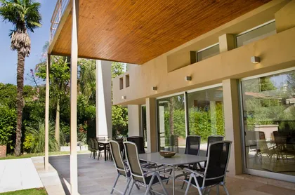Patio moderno cubierto con techo de madera y comedor exterior — proyecto Casa en San Isidro, por GEN STUDIO COMOTTO - SOMMER , en San Isidro