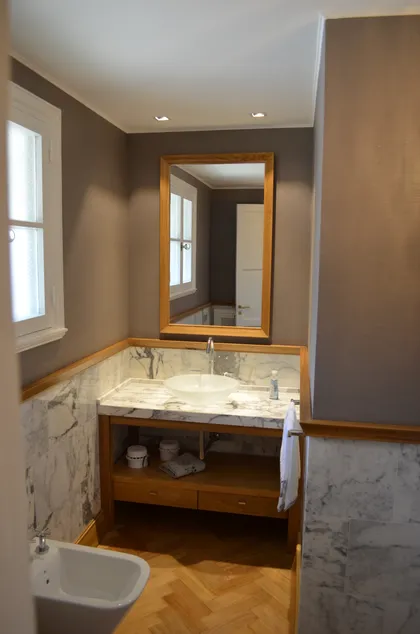 Baño moderno con vanitory de mármol y suelo de madera — proyecto Casa en Barrio El Jockey - San Isidro, por GEN STUDIO COMOTTO - SOMMER , en San Isidro