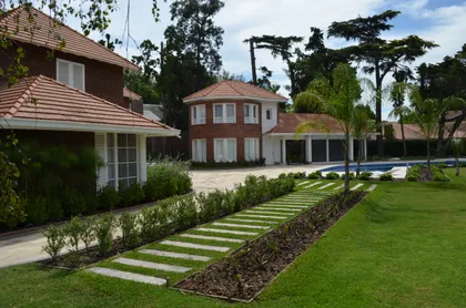 Fachada moderna con tejas y piedra, pasarela con césped — proyecto Casa en Barrio El Jockey - San Isidro, por GEN STUDIO COMOTTO - SOMMER , en San Isidro
