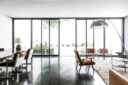 Living moderno con ventanales grandes y sillones de cuero marrones — proyecto Belgrano, por Estudio Magrane, en Belgrano