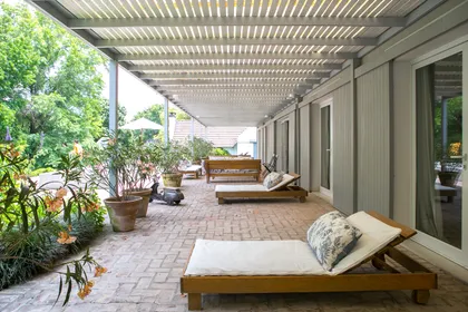 Galeria exterior con techo de pérgola de madera y muebles de exterior — proyecto Pilar, por Estudio Magrane, en Pilar
