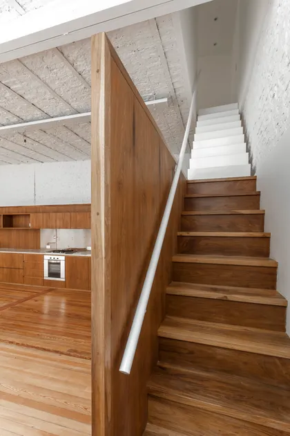 Escalera flotante de madera y cocina moderna en loft industrial — proyecto PH Tamborini , por ariana werber arquitecta, en Núñez
