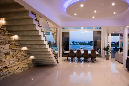 Comedor moderno con escalera flotante y vista costera — proyecto La Reserva Cardales I, por ARQCONS, en Los Cardales