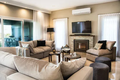 Living moderno con sofá curvo y chimenea de piedra — proyecto Casa Reserva Cardales II, por ARQCONS, en Los Cardales