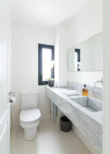 Baño moderno con lavabo de mármol integrado y ventana estrecha — proyecto Boating I, por Estudio Arq. Ana M. Carrera, en Boating Club