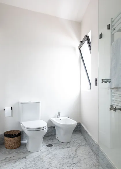 Baño moderno minimalista con suelo de mármol, bidet y claraboya — proyecto Boating I, por Estudio Arq. Ana M. Carrera, en Boating Club
