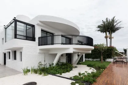 fachada moderna blanca con muros curvos y deck — proyecto Boating I, por Estudio Arq. Ana M. Carrera, en Boating Club
