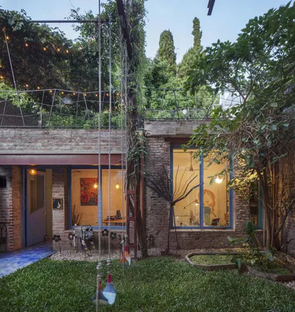 fachada moderna con ladrillo expuesto y vegetación exuberante — proyecto Casa Warnes, por Silvia Soqueff, en CABA