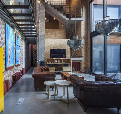 Living industrial con sofás chesterfield y doble altura — proyecto Casa Lavalle, por Silvia Soqueff, en CABA