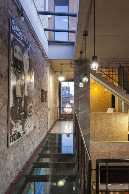 Pasillo industrial con escaleras flotantes de vidrio y pared de ladrillo expuesto — proyecto Casa Lavalle, por Silvia Soqueff, en CABA