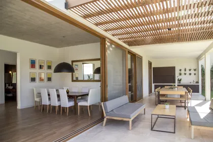 Comedor y sala semi-cubiertos con techo de madera y grandes ventanales — proyecto LS 624, por Grupo Pauta Arquitectura