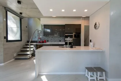 Cocina moderna con isla y paredes de hormigón — proyecto Casa G y G, por TAVA Coop, en Cariló