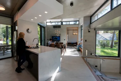 Cocina moderna integrada con isla de mármol y ventanas amplias — proyecto Casa G y G, por TAVA Coop, en Cariló