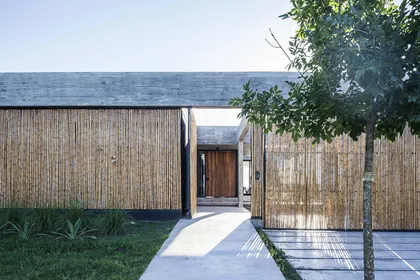 Fachada de casa moderna con revestimiento de bambú y concreto — proyecto Bamboo House, por Estudio PK