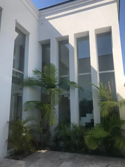 Fachada moderna con plantas tropicales y ventanales altos — proyecto San Isidro Labrador, por GreenArq - Carolina Faverio , en San Isidro