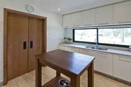 Cocina contemporánea con isla central, mesada madera y muebles blancos minimalistas — proyecto La Tahona, por BAS Y GARCIA , en Canelones Departamento de Canelones