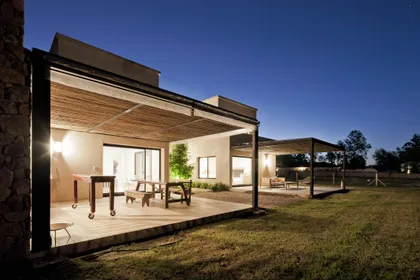 Galería moderna iluminada al atardecer con estructura de madera y vidrio — proyecto La Tahona, por BAS Y GARCIA , en Canelones Departamento de Canelones