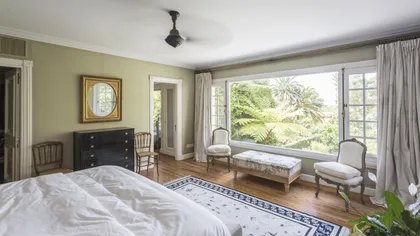 Dormitorio principal luminoso con ventanal hacia jardín y piso de madera — proyecto The Classic, por BAS Y GARCIA , en San Isidro