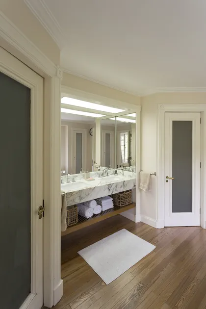 Baño moderno con mesada de mármol y espejo grande iluminado — proyecto The Classic, por BAS Y GARCIA , en San Isidro