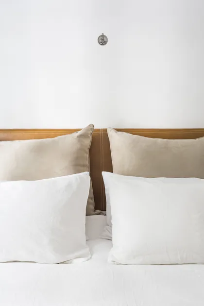 Cama minimalista con almohadas blancas y estructura madera clara — proyecto Arenales, por BAS Y GARCIA , en Recoleta