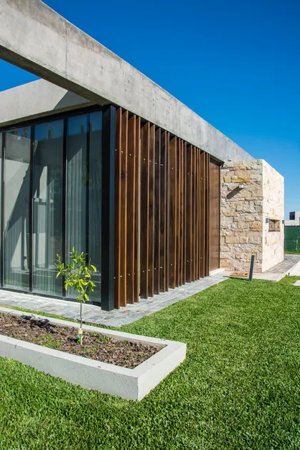 Casa moderna con fachada mixta piedra hormigón y celosía madera — proyecto CASA SI, por DX ARQ