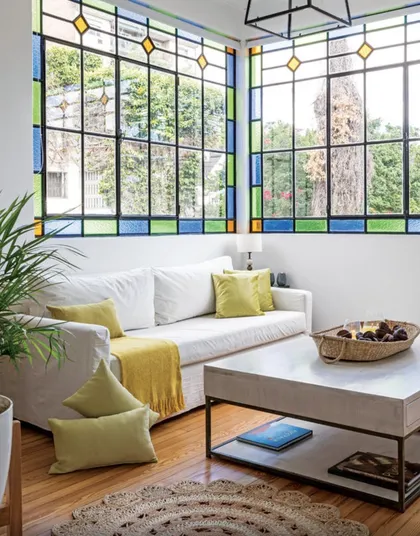 Living con ventanal coloreado, sofá blanco y cojines amarillos — proyecto Olivos, por Biaus Pieres Arquitectura