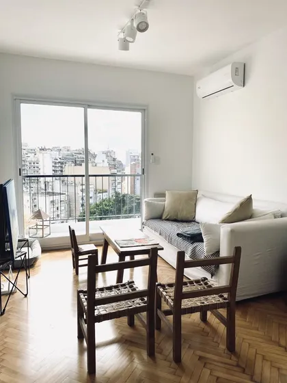 Living con balcón, muebles de madera y vista a la ciudad — proyecto Melo, por Biaus Pieres Arquitectura, en CABA