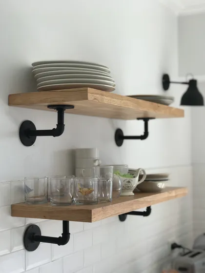 Estantes flotantes de madera con herrajes industriales negros en cocina — proyecto Peña, por Biaus Pieres Arquitectura, en Recoleta