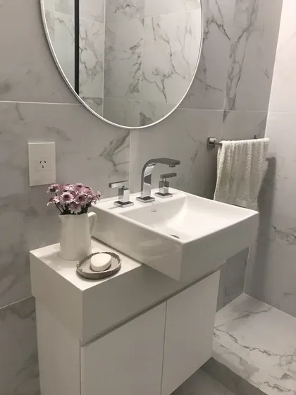 Baño minimalista con mármol, espejo circular y detalles en gris — proyecto Billinghurst , por Biaus Pieres Arquitectura, en CABA