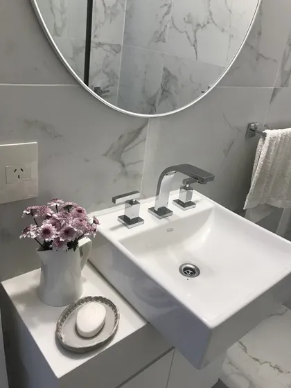 Baño moderno minimalista con mesada en mármol y espejo circular — proyecto Billinghurst , por Biaus Pieres Arquitectura, en CABA