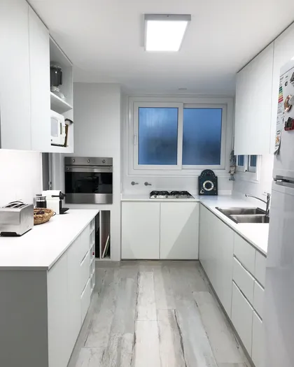Cocina moderna blanca con mesadas de mármol y ventanal al exterior — proyecto Paraná , por Biaus Pieres Arquitectura, en CABA