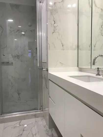 Baño moderno con marmol, ducha cristal y mesada blanca minimalista — proyecto Paraná , por Biaus Pieres Arquitectura, en CABA