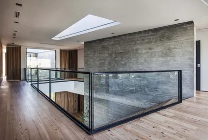 Pasillo de doble altura con escalera y barandal de vidrio ahumado — proyecto Casa India , por Estudio Simbiosis