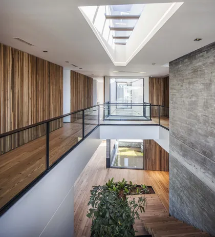 Pasillo con doble altura, skylight cenital y barandal metálico negro — proyecto Casa India , por Estudio Simbiosis